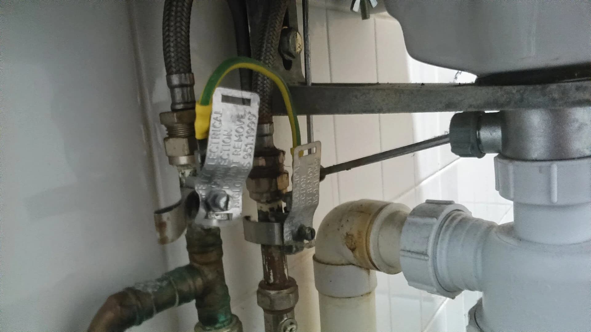 Pipa pembuangan, sifon, dan selang air di bawah wastafel yang dicek untuk kebocoran