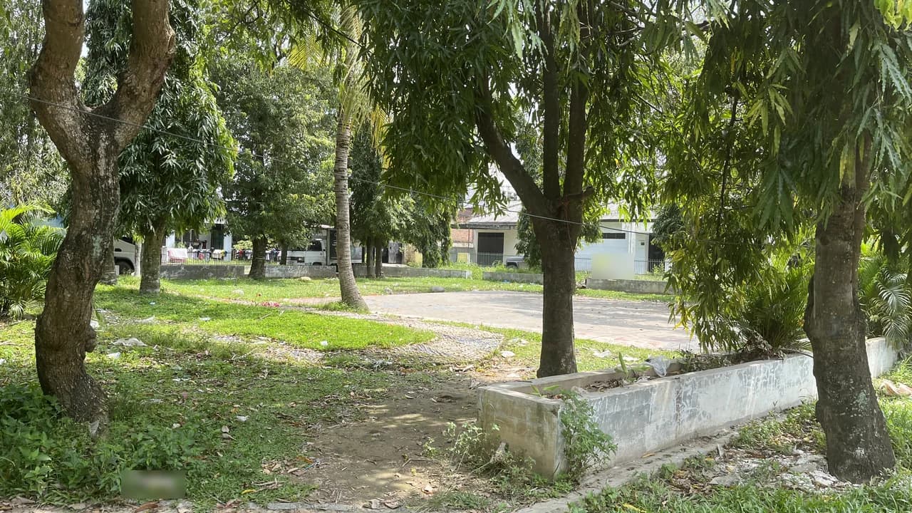 Taman kompleks perumahan di Kota Medan dengan pohon peneduh dan lapangan paving, bukan foto proyek Inproland