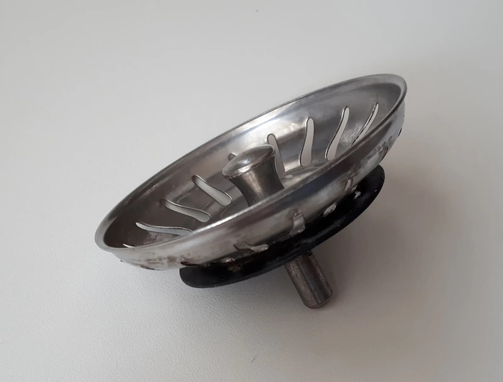 Saringan wastafel stainless steel dengan cincin karet hitam di atas permukaan putih, bukan foto proyek Inproland
