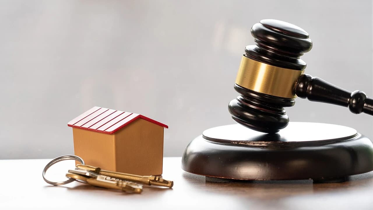 Miniatur rumah kayu, kunci rumah, dan palu hakim sebagai ilustrasi jaminan properti