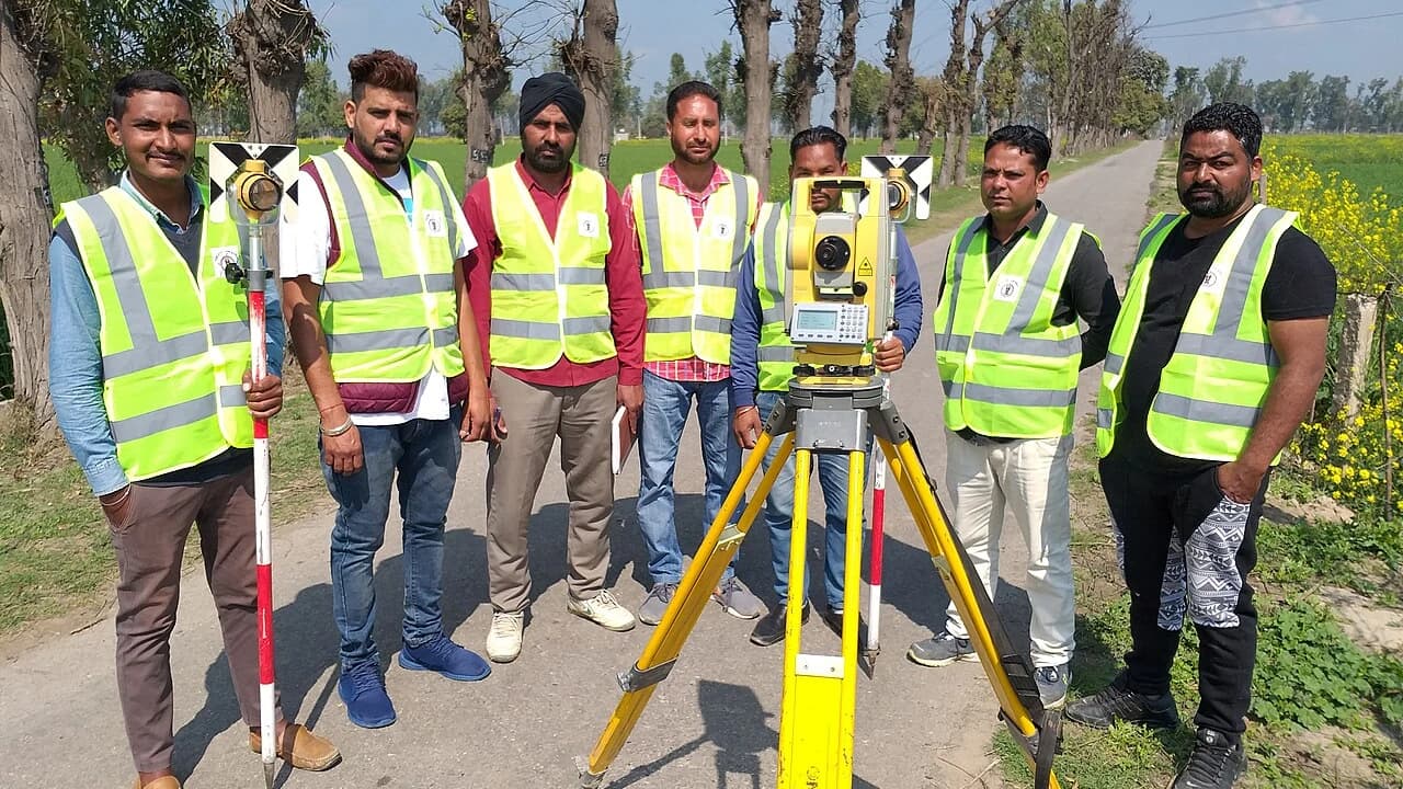 Tim juru ukur memakai total station di tripod untuk pengukuran tanah