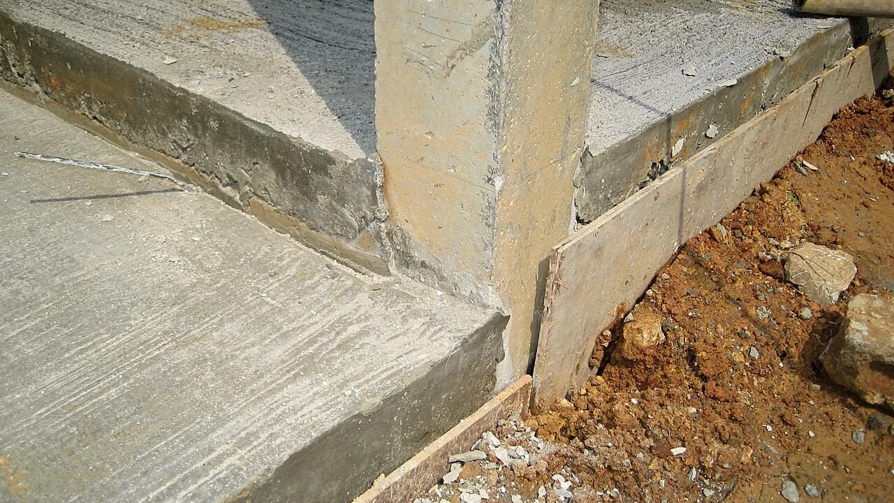 Sudut pelat lantai beton rumah dan kolom di atas tanah, memperlihatkan beda tinggi lantai terhadap muka tanah